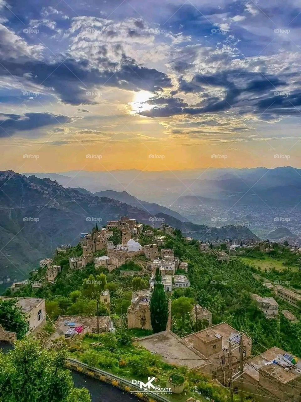 The image embodies a natural natural plate of the mountains of nature, where green agricultural stands are graded on the slopes as if they were lines of a poem, which fog harmoniously wrapped, and clouds hugged them in the mountain knife and the whis