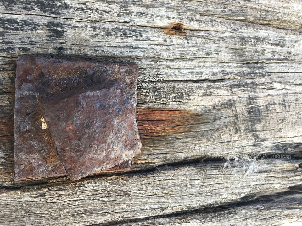 Closeup textural image of piling post on 100 year old wharf dock with rusted iron stake