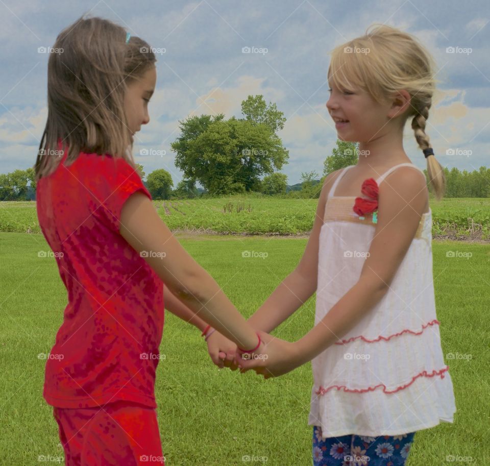 Two sisters holding hands in the green field