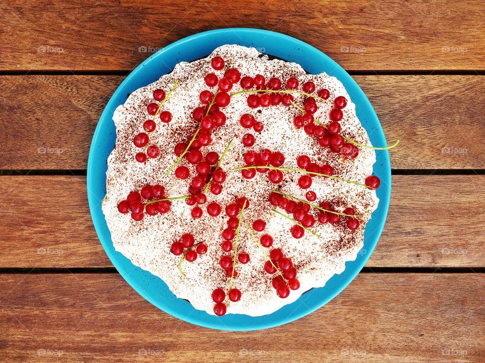 Brownie cake covered with whipped cream and red curratns