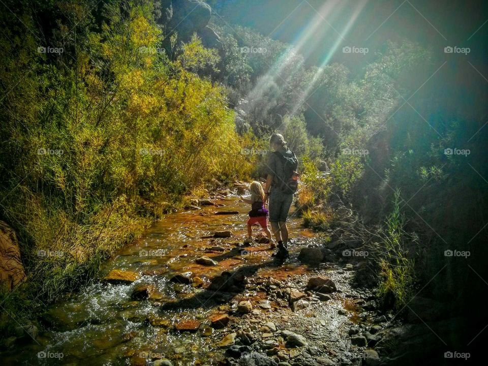 hiking through the river. helping a little girl hike through the water