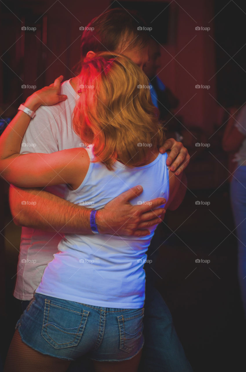 people dancing Kizomba close to each other in the night club, red lightning around 