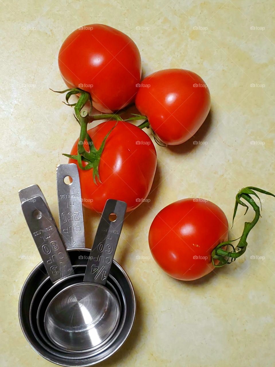 vine ripe tomatoes and stainless steel measuring cups, and butter sticks on a kitchen counter top