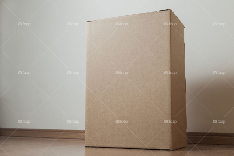 Cardboard box with order placed on the floor in an empty room with a neutral background. delivery concept. economy concept. business concept. shopping concept. copy space. Nobody