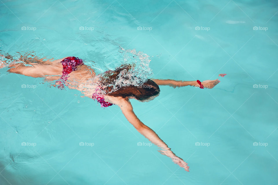 Young woman swimming and relaxing in swimming pool. Candid people, real moments, authentic situations