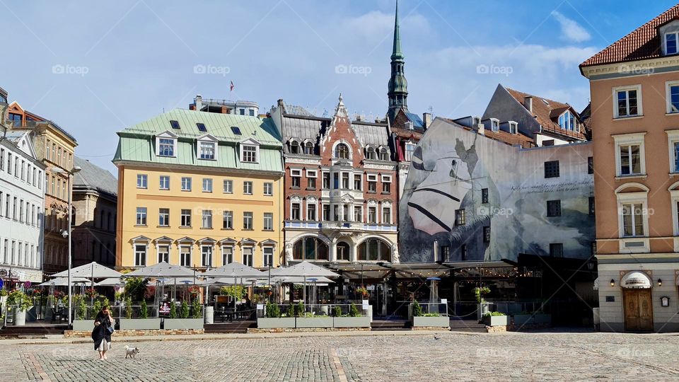 woman and dog walking along the square in the old town of Riga