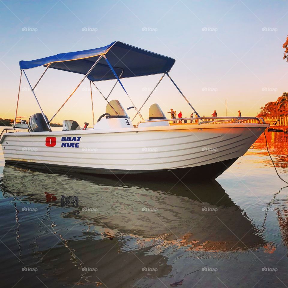 The boat with a blue shade on the clear water at sunset 