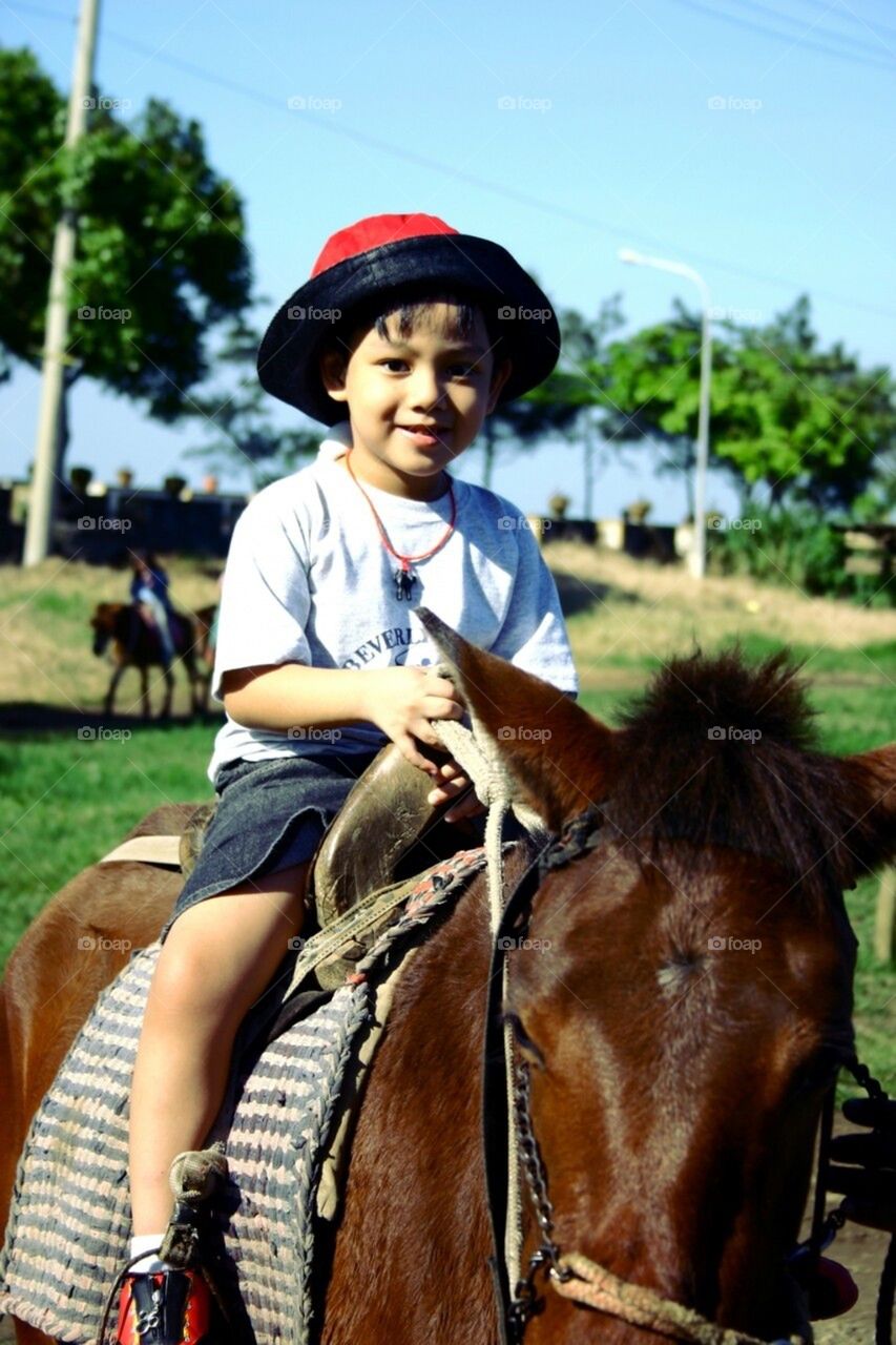 Little asian boy riding a horse