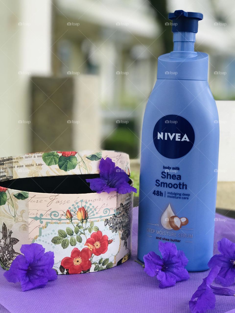 Nivea shea smooth body lotion with purple colour flowers and beside that gift box.