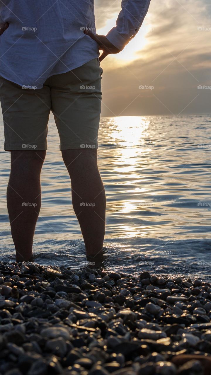 Sunset on the sea. Men's legs