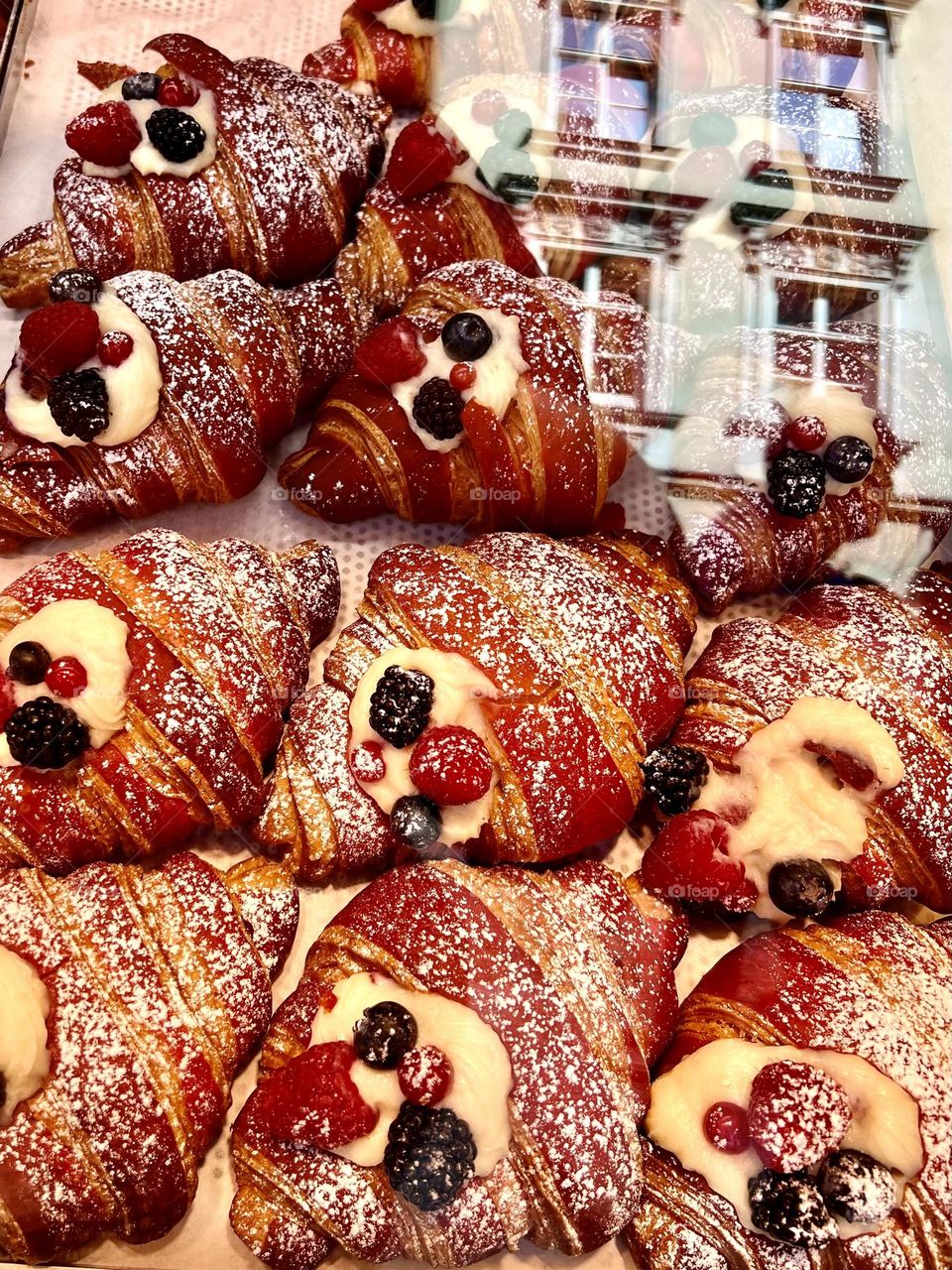 The photo shows delicious croissants generously decorated with fresh berries. The golden, flaky crust of the croissants contrasts with the bright colors of raspberries and blueberries