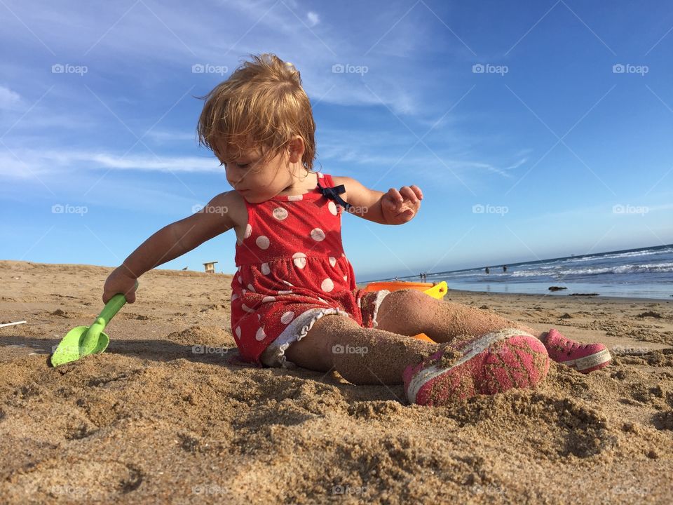 Little girl playing at beach with sand