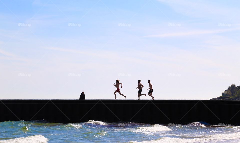 Let's go swimming. People running on the jetty to jump in the sea