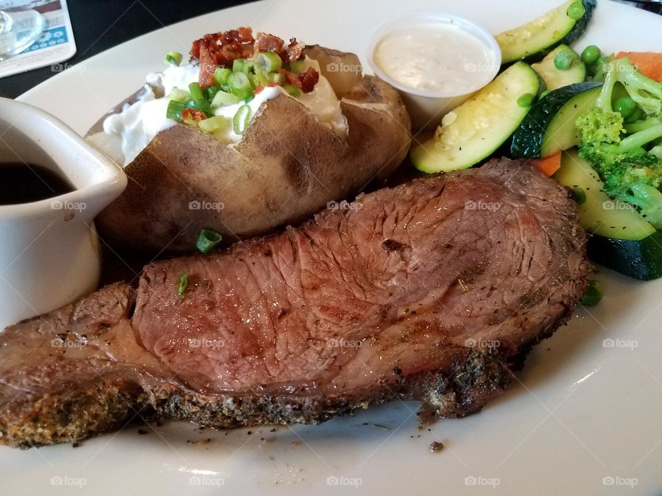 Perfect prime rib dinner with loaded baked potato and seasonal fresh vegetables, served with horseradish sauce and au jus.