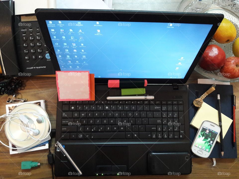 modern table top view laptop telephone phone mobile pens papers ear phones keys book watch switch on computer switched power on mobile screen activity compact disk cd