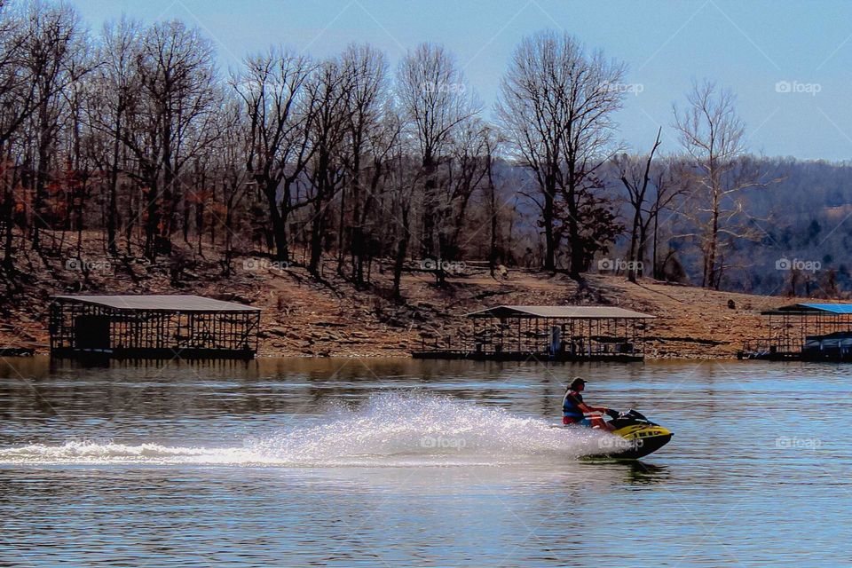A man riding a jet sky on a lake on a warm late March  early spring day. 