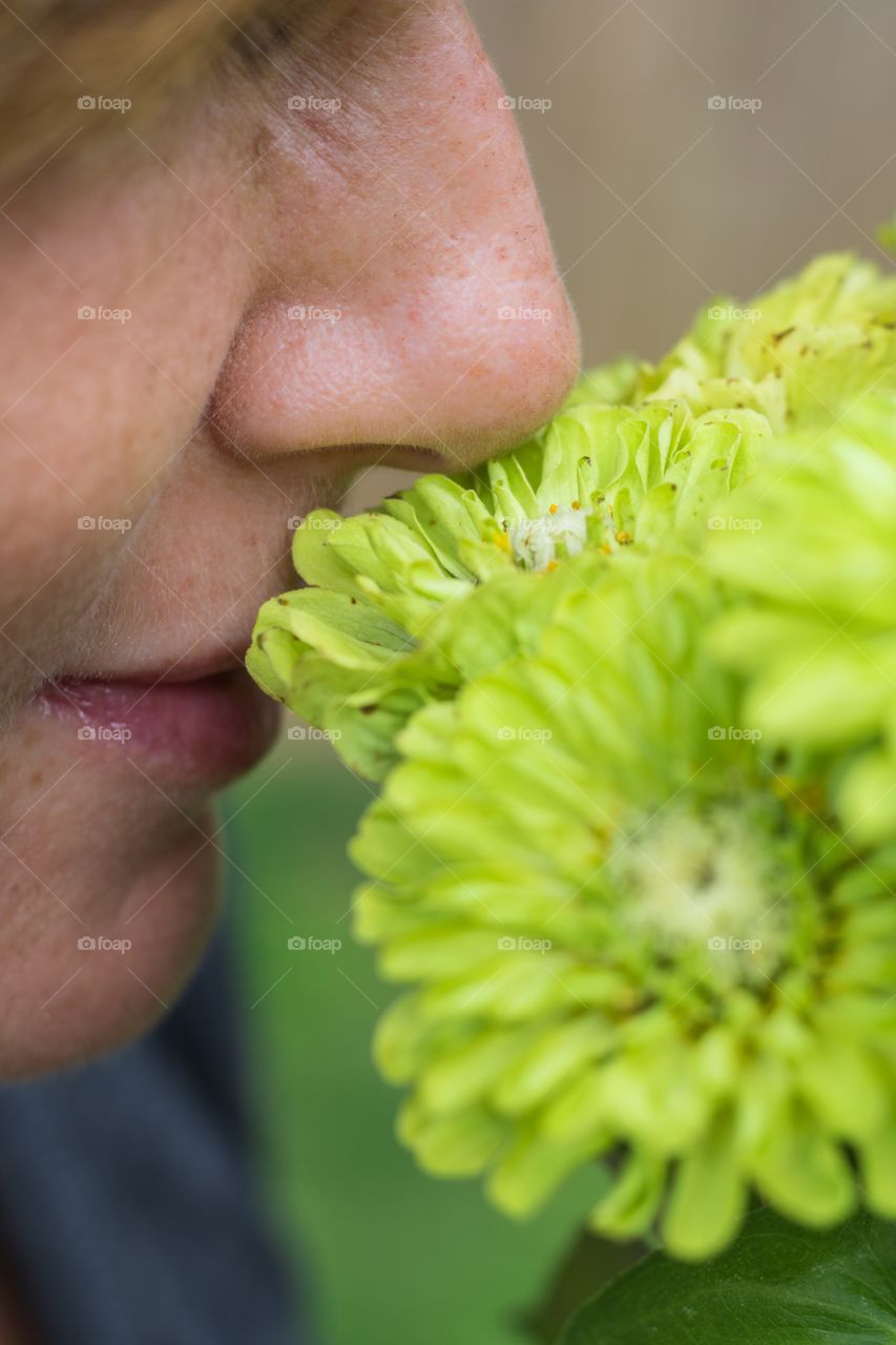Vertical closeup photo of a Caucasian woman smelling a bouquet of green flowers