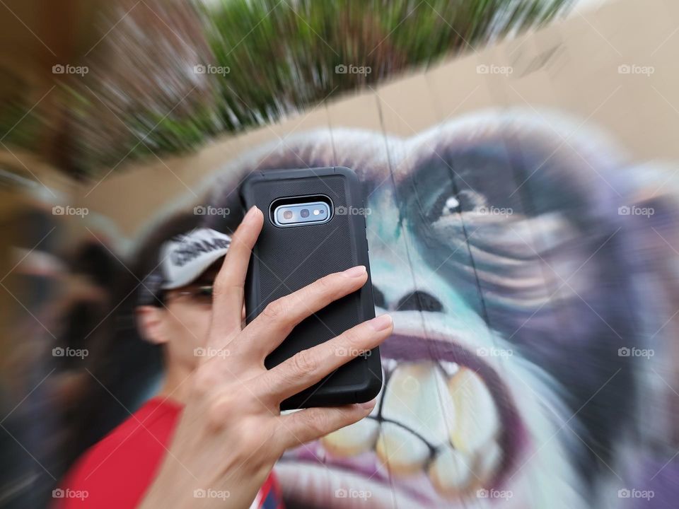 A man taking a selfie with crazy ape art mural.