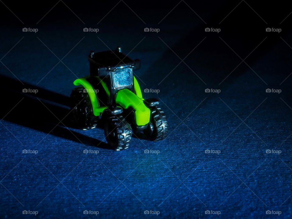 Toy agricultural machinery tractor black and green on a dark background