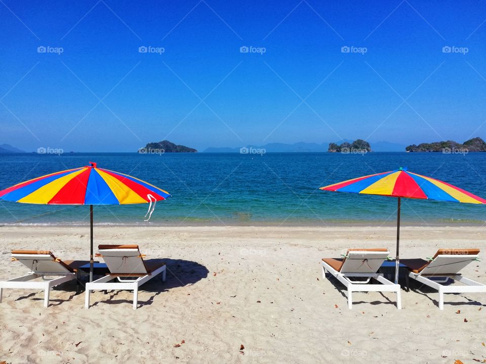 Two colorful beach umbrellas on a deserted Malaysian beach