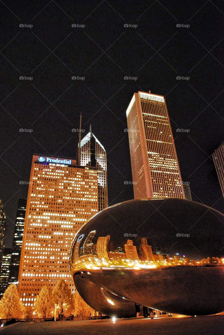 Cloudgate below skyscrapers. Cloudgate sculpture reflecting the brilliant lights of Chicago's cityscape  on a summer night