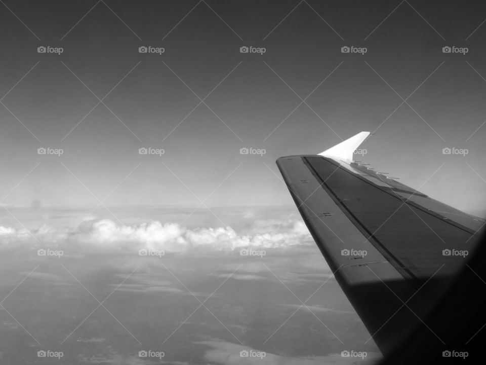 Black and white shot of airplane wing against sky over Spain.