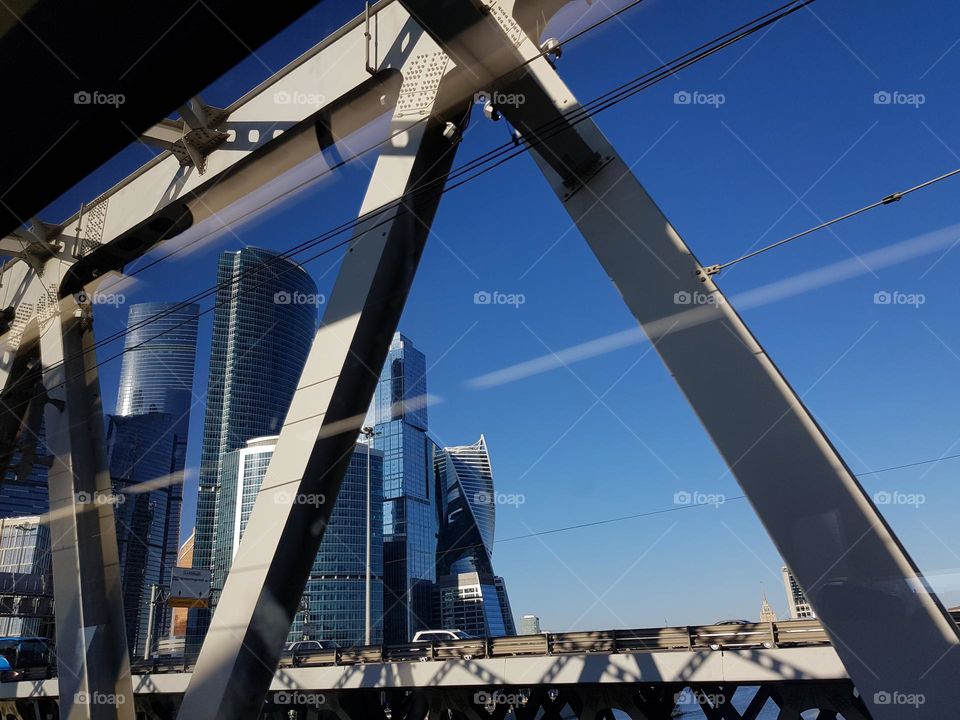 View on high, shiny skyscrapers while approaching over a steel bridge