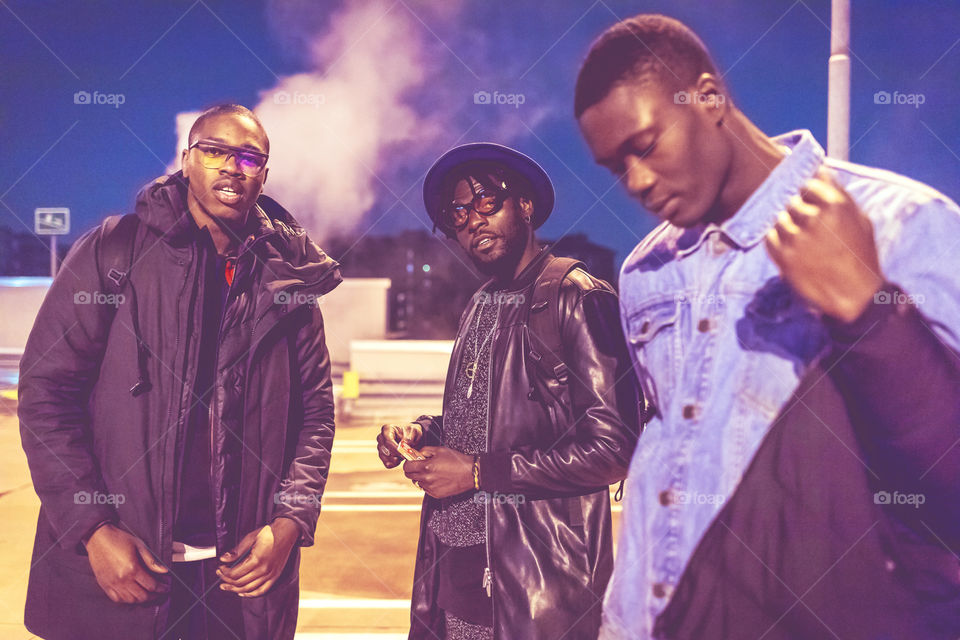 Black young handsome group of friends looking at camera by night in the street - street fashion concept, black lives matter, united, friends