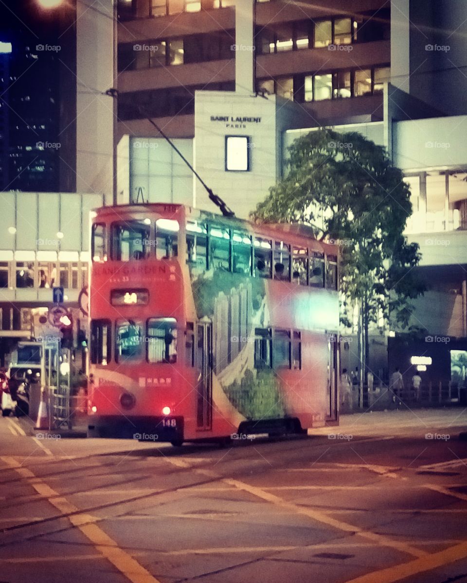 The picture was taken in Hong Kong. The big red bus on a night road of the city centre.