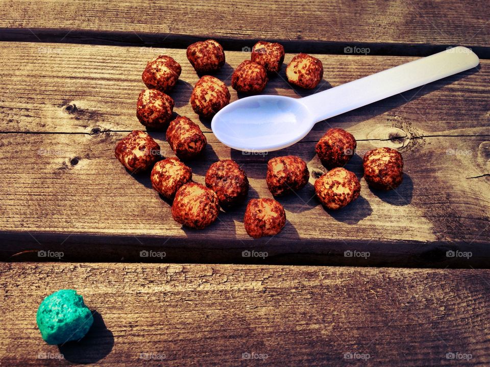 The brown snack balls huddle around the spoon, wondering what it is, while the blue ball knows better.