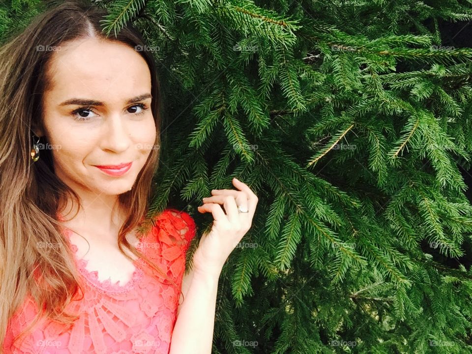 Portrait of woman with red lips surrounded by pine cone trees