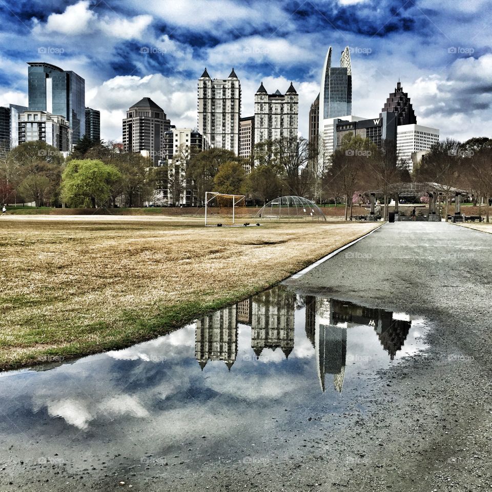 Reflection of skyline in puddle at park