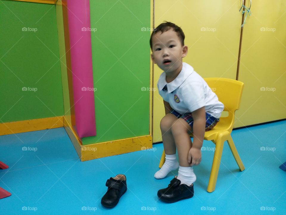 boy pauses while putting on a shoe
