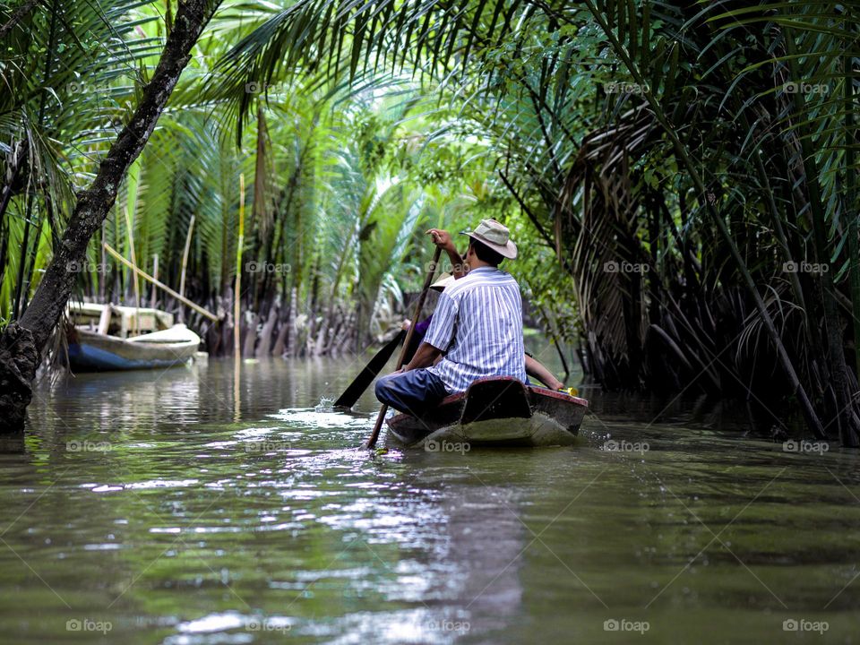 A man rowing a sampan in a mangrove waterways in Vietnam