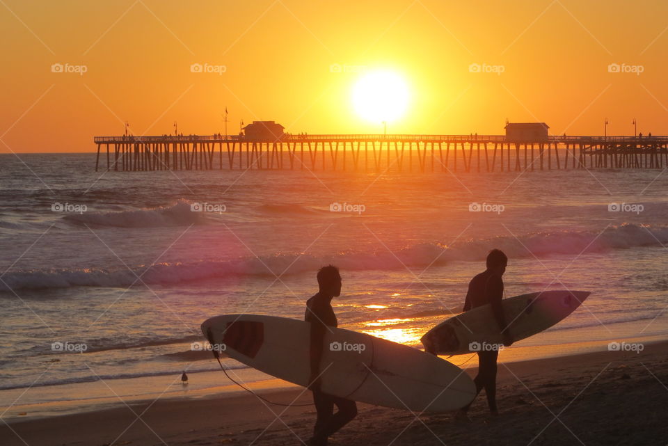 Sunset Surfers. Surfers walking on beach at sunset