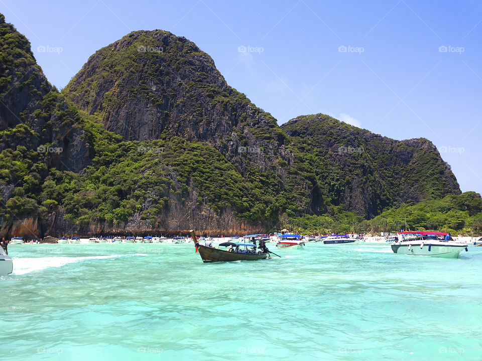 Many boats swimming in the blue sea at the tropical beach nearby island 