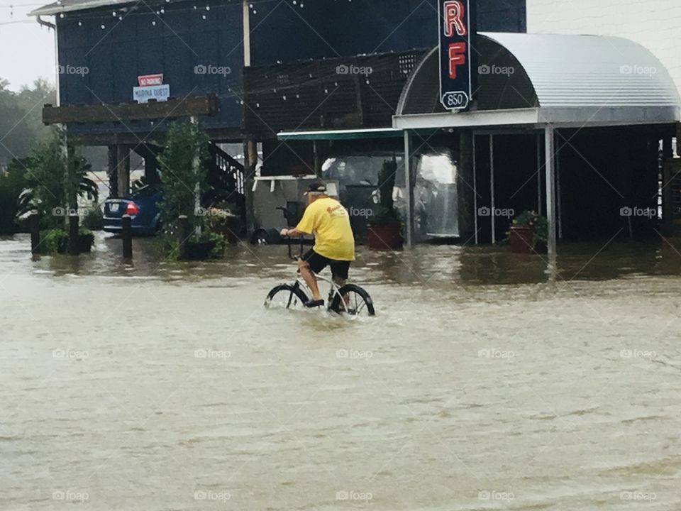 Man rides bicycle throw flooded street as a result of Hurricane Sally. 