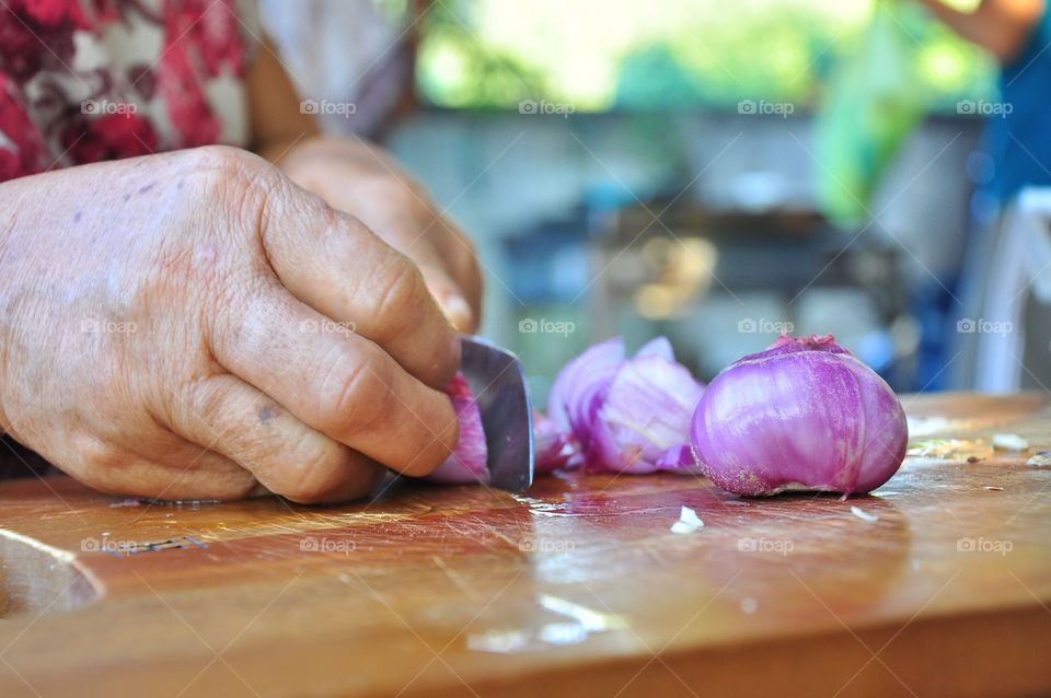 Close-up of women's hand chopping onion on cutting board