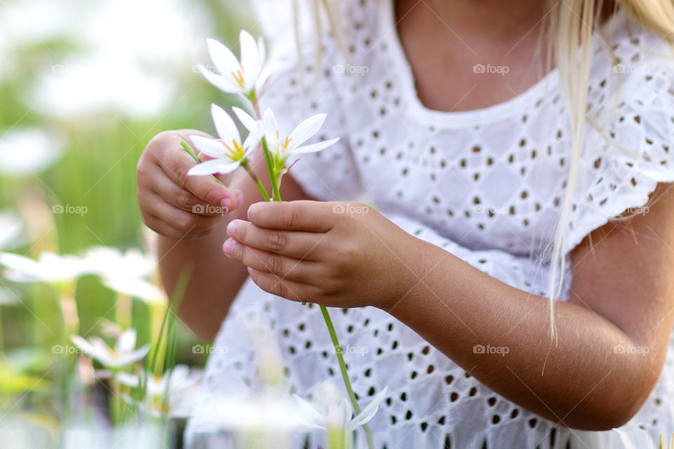 Little girl holding hands bouquet of white flowers 