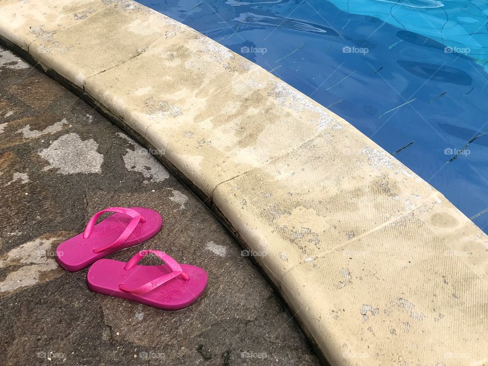 Children's pink flip flops by the pool