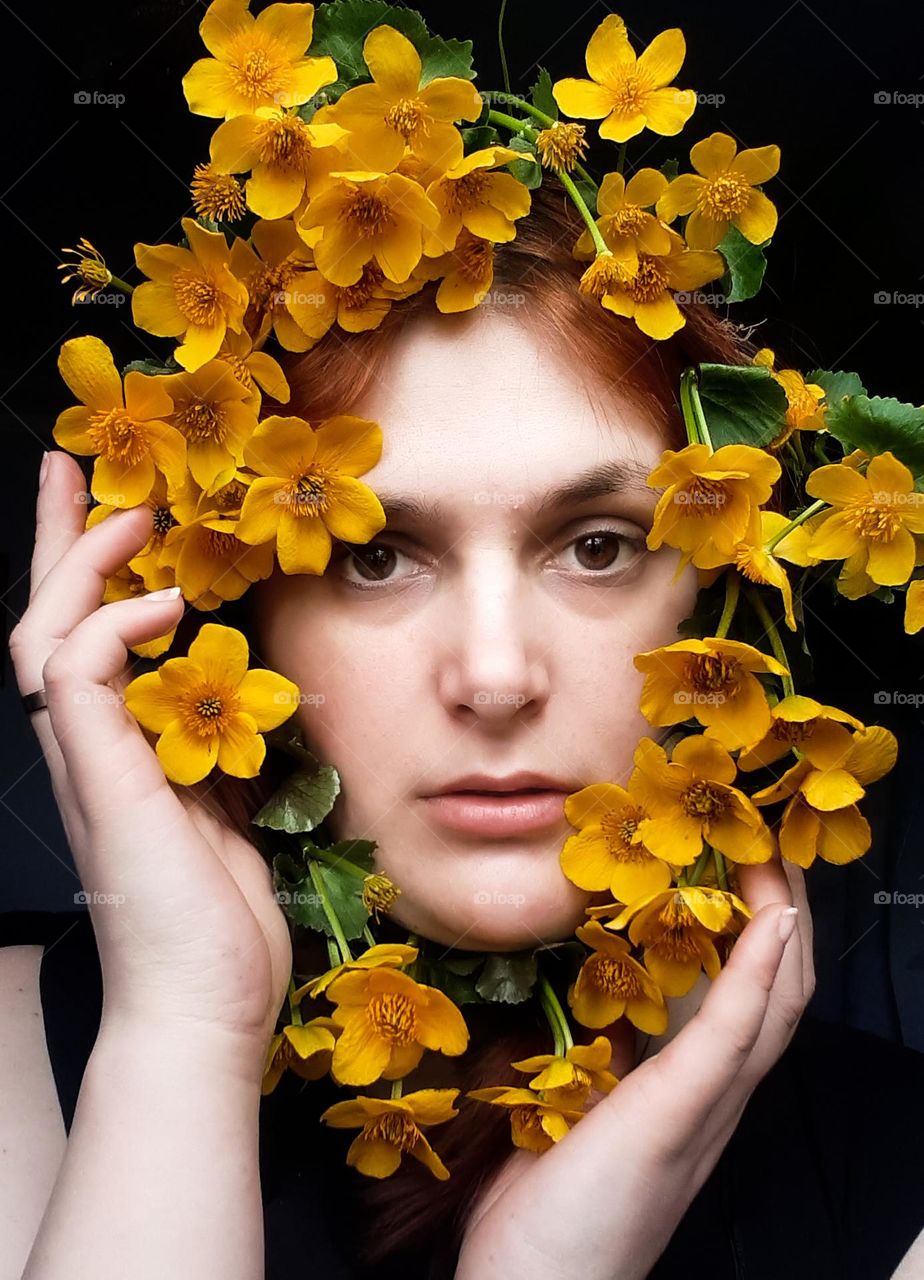 a female portrait of a fair-skinned girl with yellow flowers, namely a female face among spring flowers