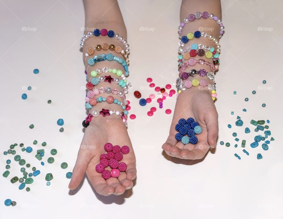 Girl shows the many colourful beads she uses to make bracelets at home 
