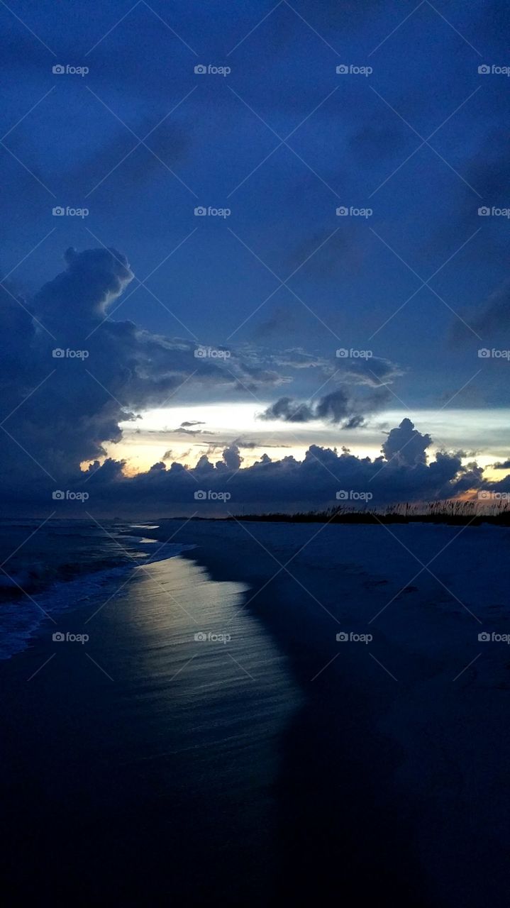 Surf at sandy beach during sunset