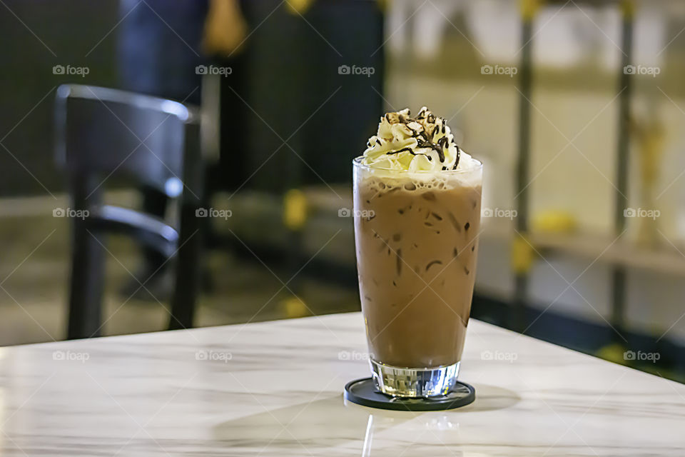 Iced cocoa put whipped cream in a glass on the table.