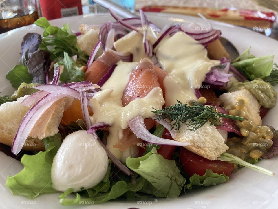 Salad with salmon, mozzarella, cherry tomatoes, onion, sauce and croutons 