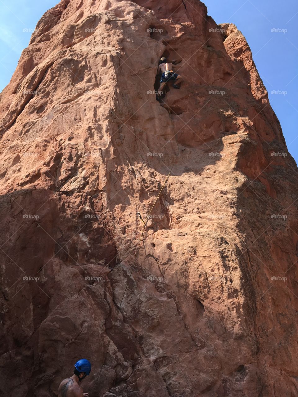 Climber on the red-orange rock of Garden of the Gods with blue sky above