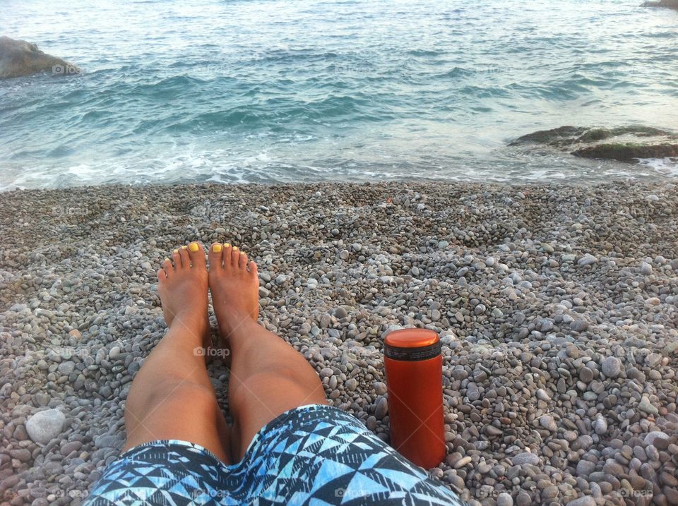 Feet with coffee at the sea