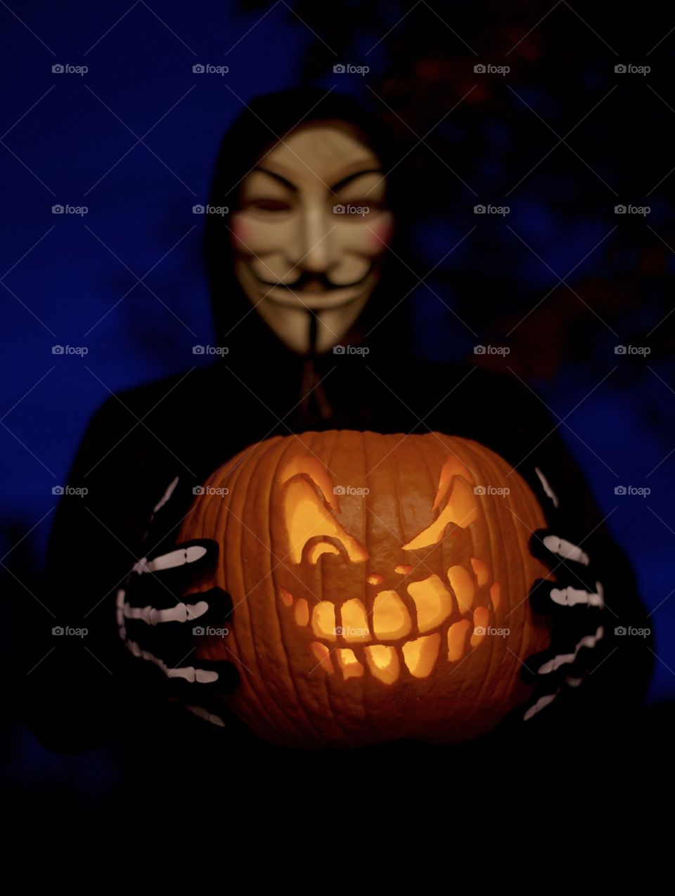 Halloween costume, guy Fawkes mask and carved jack-o’-lantern