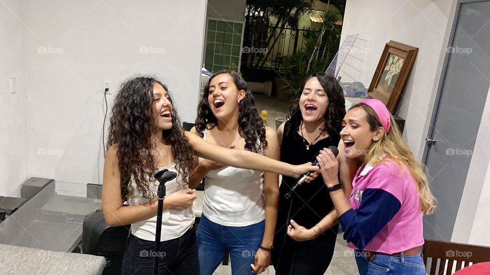 Group of women singing an emotional song, enjoying the karaoke, at the midnight.