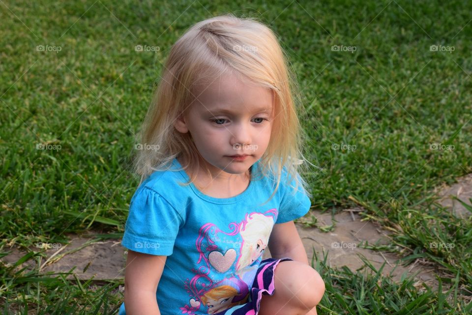 Toddler sitting outside. Girl sitting in the grass